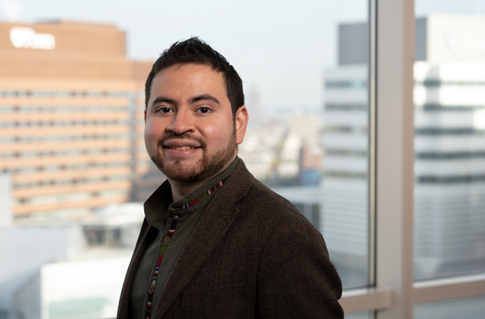 A headshot of Juan Alvarez, an assistant professor of Cell and Developmental Biology, standing in front of a window